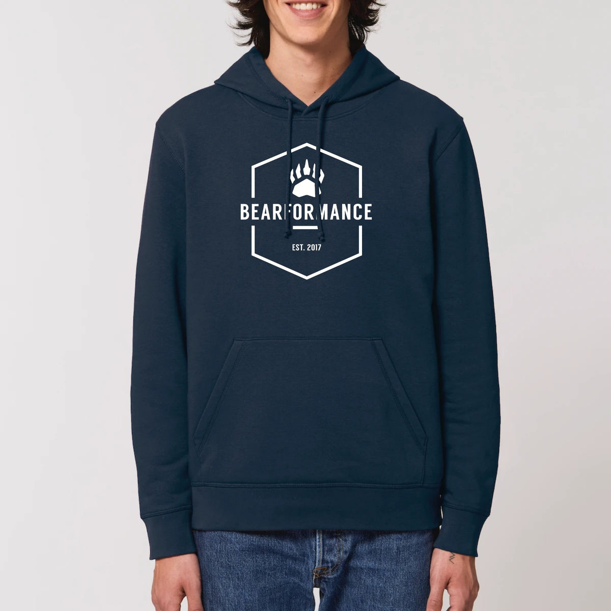 Mann trägt dunkelblauen BEARFORMANCE Unisex Hoodie aus Bio-Baumwolle mit weißem Logo-Emblem