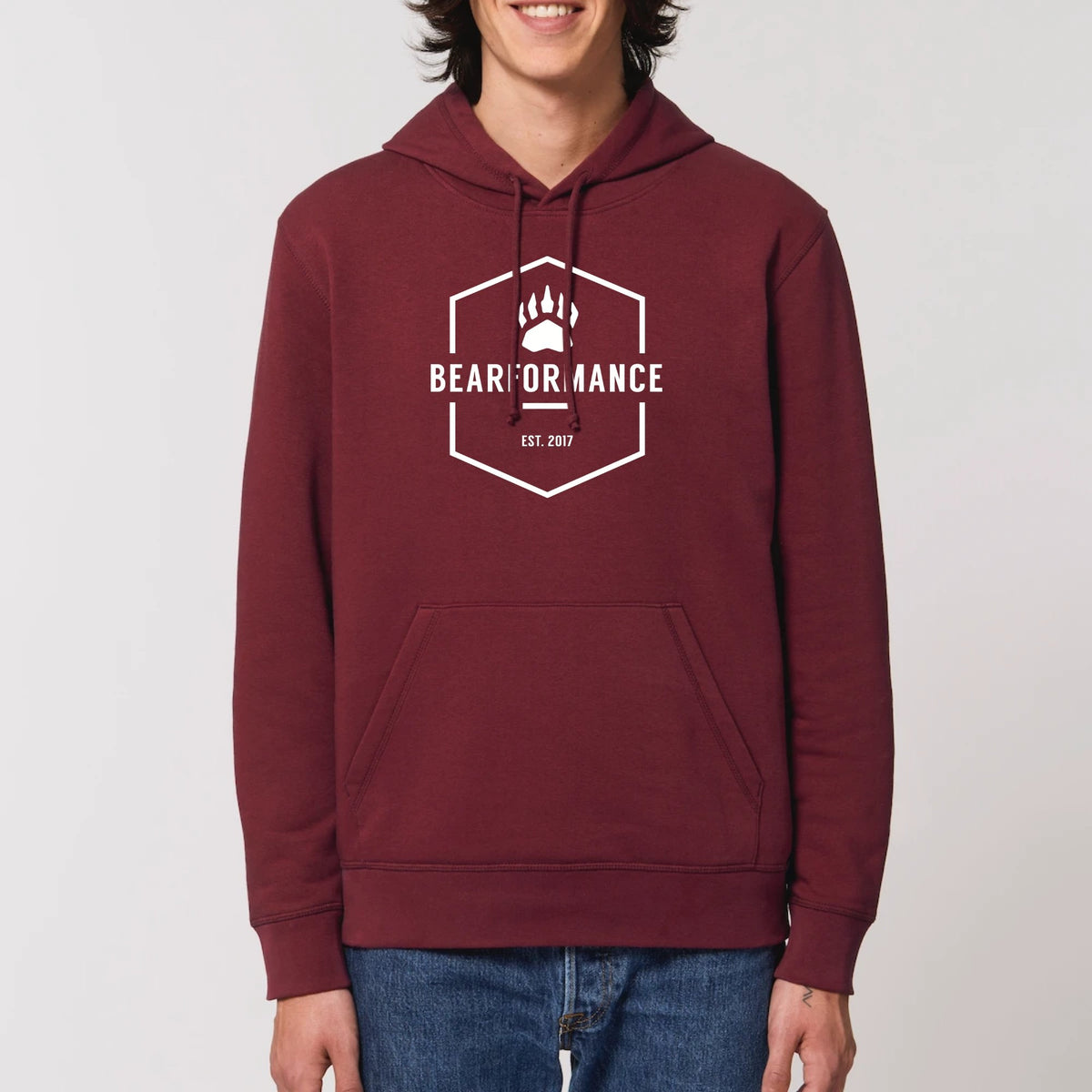 Mann trägt bordeauxroten BEARFORMANCE Unisex Hoodie aus Bio-Baumwolle mit weißem Logo-Emblem