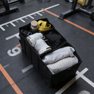 BEARFORMANCE Divider in Schwarz auf dem Gym-Boden, gepackt mit Sneakern, Handtüchern und Trinkflasche – Ordnungssystem mit drei Fächern